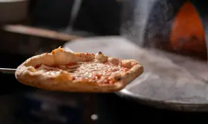 Gorąca pizza z serem i sosem pomidorowym wyjmowana z pieca.